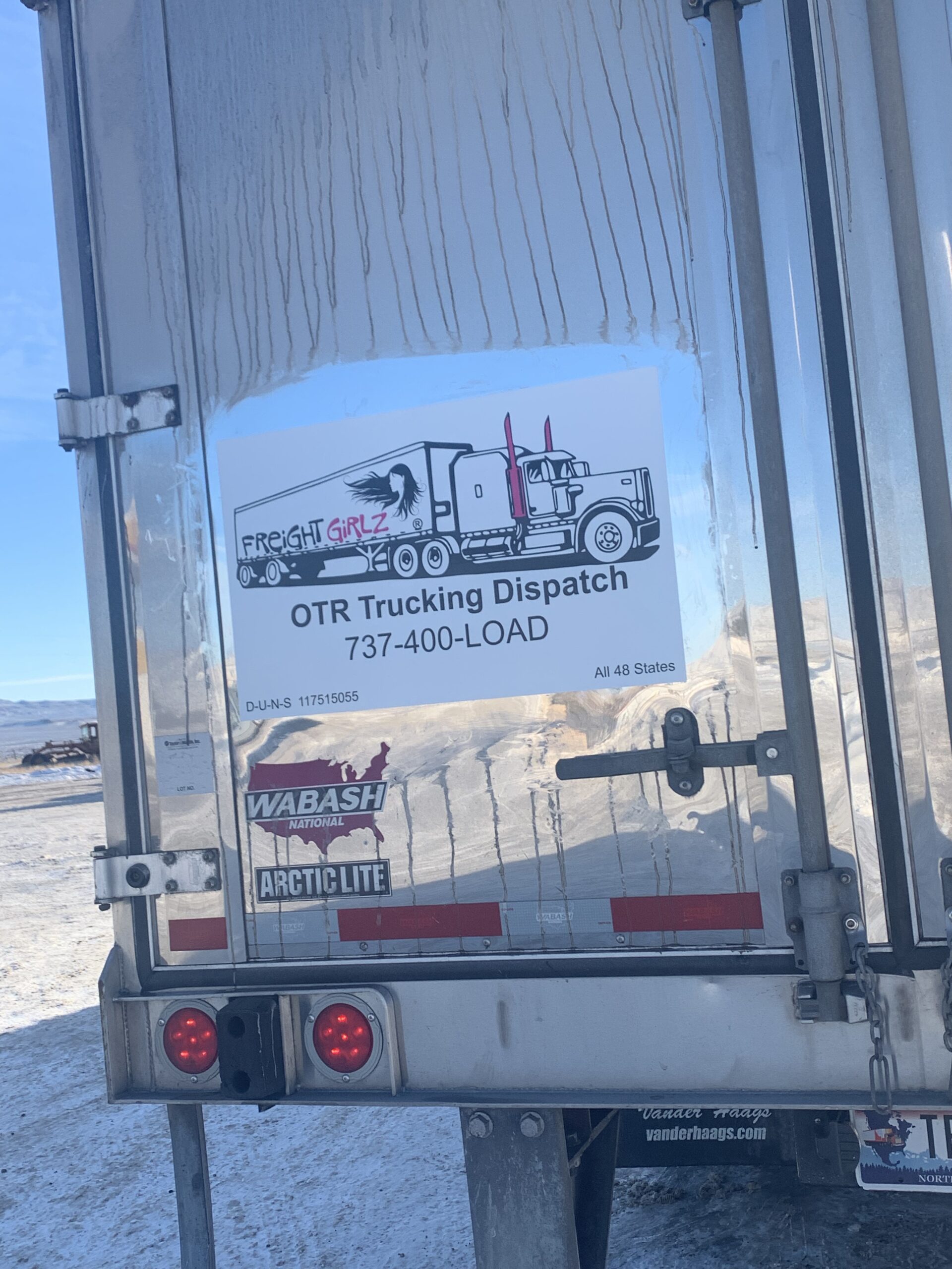 Freight Girlz OTR trucking dispatch sign displayed on the back of a trailer, showing the Freight Girlz logo, phone number 737-400-LOAD, and service across all 48 states.